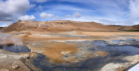 barren landscape of a geothermal area with soil in the colors of orange, yellow, blue, gray, white