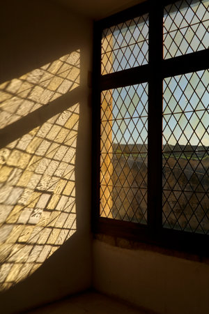 Sunlight casting patterned shadows through a medieval leaded-glass window