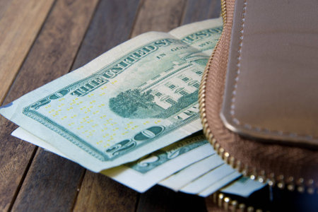 Open the purse and money sticking out. Photo taken on wooden background.