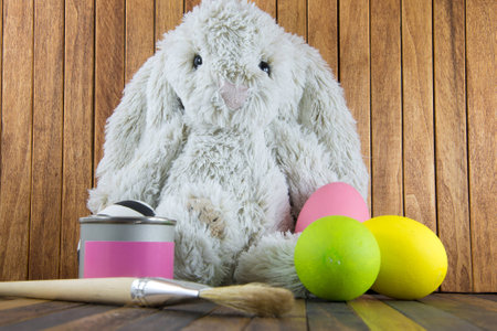 Rabbit (bunny) and Easter Egg and jar of pink paint on wooden background