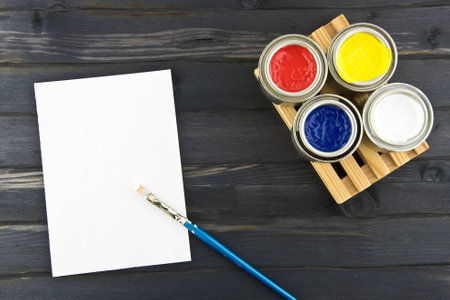 The jars of paints on the pallet and white paper on a wood backgroundの写真素材