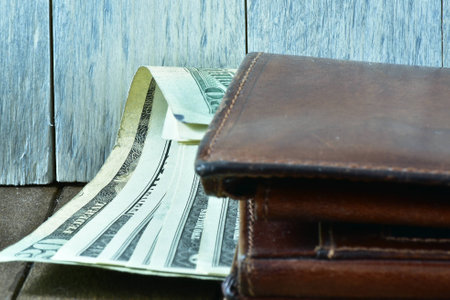 brown men's wallet and dollars on wooden backgroundの写真素材