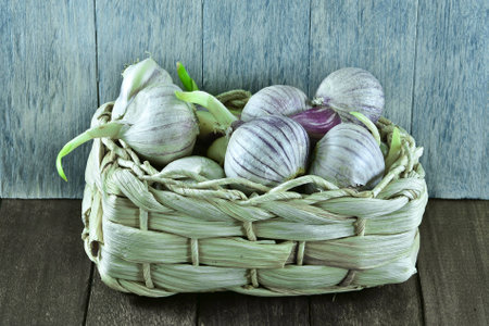 Garlic in the basket on wooden tableの写真素材