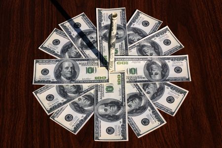 Sundial with a dial from paper money on the isolated wooden backgroundの写真素材