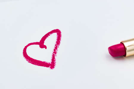Pink heart sign drawn with a lipstick isolated on white background