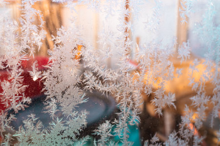 Cold winter morning ice flowers on glass, background with copy space