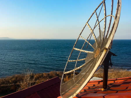 Satellite dish on the roof of the house against the background of the sea.の写真素材