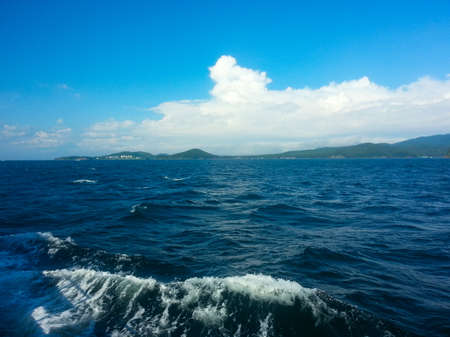 Waves from the boat in the sea and blue sky with cloudsの写真素材