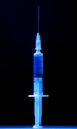 Syringe with blue liquid on a black backgroundの写真素材