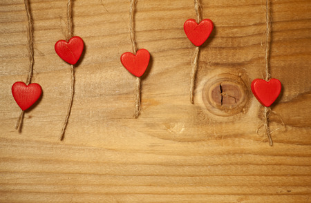 Red wooden hearts hanging on the rope. On old wood background.の写真素材