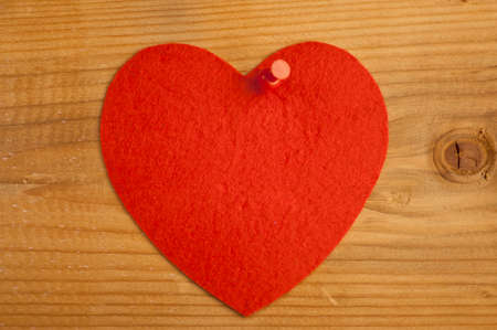 Red plush hearts hanging on the tack. On old wood background.