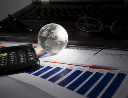 Globe and some business accessories on business documents with deep shadows.の写真素材