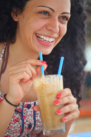 Young beautiful brunette girl drinking iced coffee and having fun の写真素材