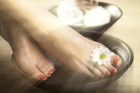 Female feet with drops of water, spa bowls, towels and flowers. Special lighting effect.の写真素材