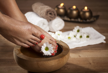 Female feet with drops of water, spa bowls, towels, flowers and candles.の写真素材