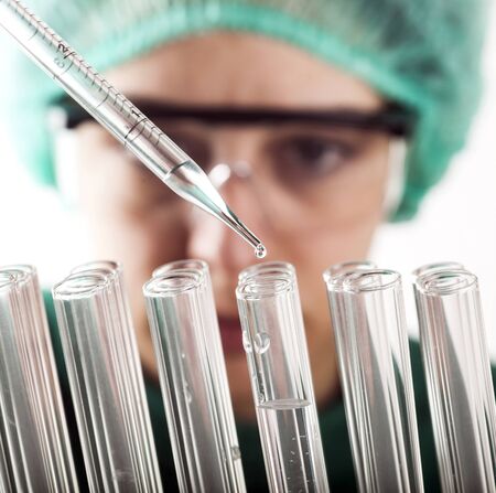 Closeup of a female scientist filling test tubes with pipette in laboratory.