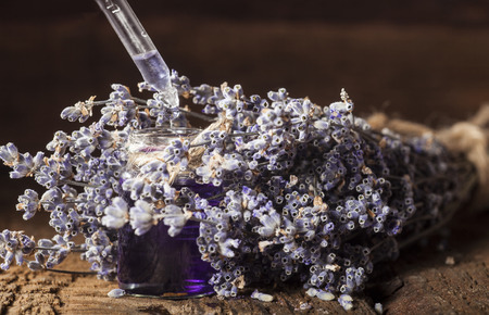 Spa background with bunch of lavender and glass vial with essential oil.の写真素材