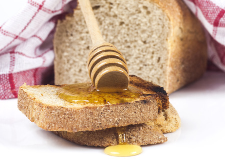 Toasted bread with honey and honey dipper isolated on white studio background.の写真素材