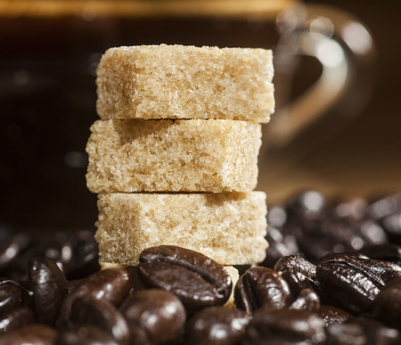 Close up of sugar cubes on coffee beans background and glass coffee cup.の写真素材