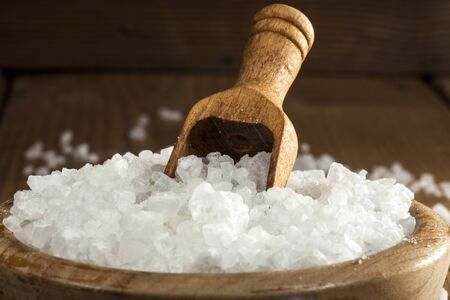 Sea salt in bowl and spoon on a wooden background.の写真素材