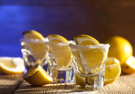 Three tequila shots with lemon and salt on wooden background.の写真素材