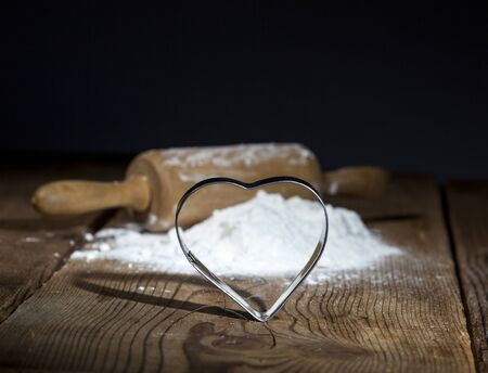 Kitchen rolling pin with flour and cookie cutter on wooden background.の写真素材