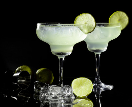 Two glasses of margarita cocktail on a black background.の写真素材