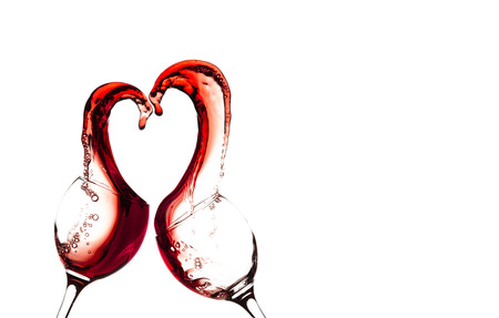 Two glasses of red wine with abstract heart splash on a white backgroundの写真素材
