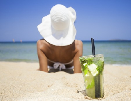 Woman with glass of fresh mojito cocktail on the beachの写真素材