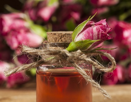 Closeup of bottle with rose essential oil on wooden background.の写真素材