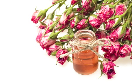 Closeup of bottle with rose essential oil on white background.