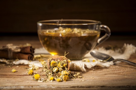 Cup of chamomile tea with chamomile flowers on wooden planksの写真素材
