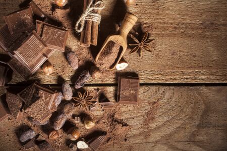 Chocolate pieses with hazelnuts, cocoa powder and cocoa grains on wooden backgroundの写真素材
