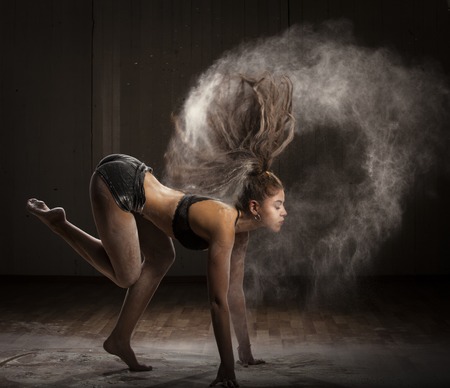 Ballerina dancing with flour on dark backgroundの写真素材