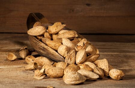 Close up of almond nuts in a bowl on wooden background