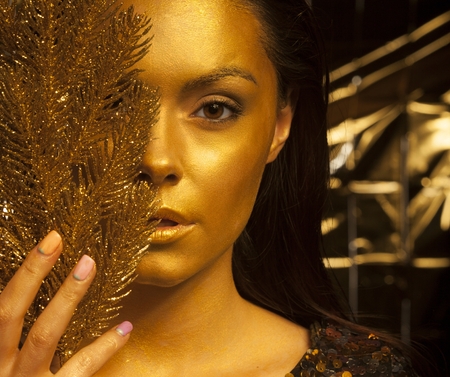 Portrait of beautiful woman with golden makeup and twigの写真素材