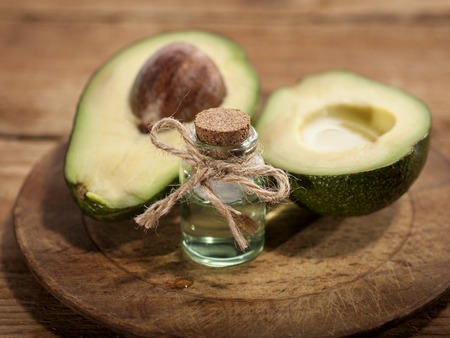 Avocado Essential Oil on wooden background. Horizontal. Front view.の写真素材