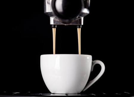 Close-up of espresso pouring from coffee machine. One cup on black background.の写真素材