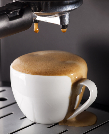 Close-up of espresso pouring from coffee machine. One cup on gray background.の写真素材