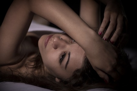 Sexy beautiful brunette woman lying in bed