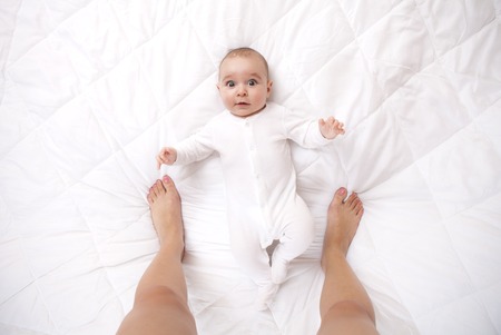 Happy addorable baby boy and the legs of his mother who taking a portrait of him.の写真素材
