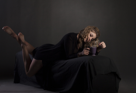 Sexy beautiful girl with cup of coffee, hot chocolate or tea in a bed.の写真素材
