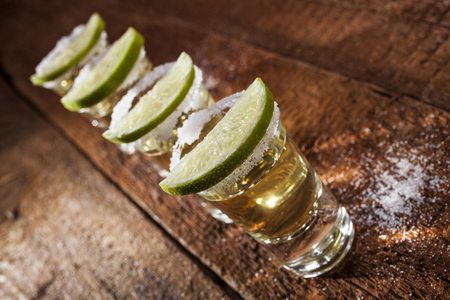 Gold tequila shots with lime fruits on wooden backgroundの写真素材