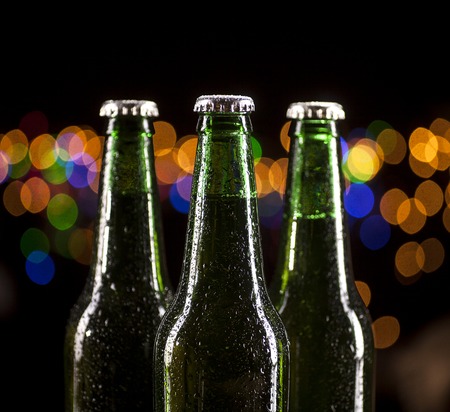 Close up of three glass bottles of beer on bar lights backgroundの写真素材