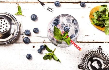 Summer cold drink with blueberry, mint and ice in glass on white wooden background. Top view.の写真素材