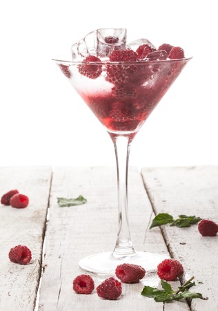 Summer cold drink with raspberry, mint and ice in glass on white backgroundの写真素材