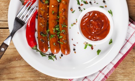 Wiener Sausages with vegetables on white plate and wooden background.の写真素材