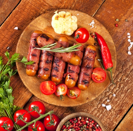 Festive cocktail sausages wrapped in crispy smoked bacon commonly known as 'Pigs in Blankets' on a wooden backgroundの写真素材
