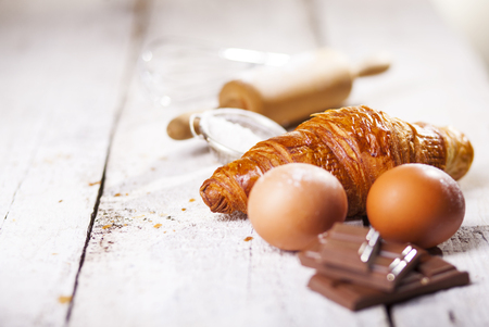 Baked croissants and ingredients for the preparation of bakery products. Rustic style. White wooden background.の写真素材