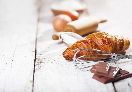 Baked croissants and ingredients for the preparation of bakery products. Rustic style. White wooden background.の写真素材